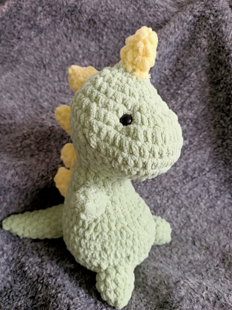 crocheted green dinosaur with yellow spikes on its head and back