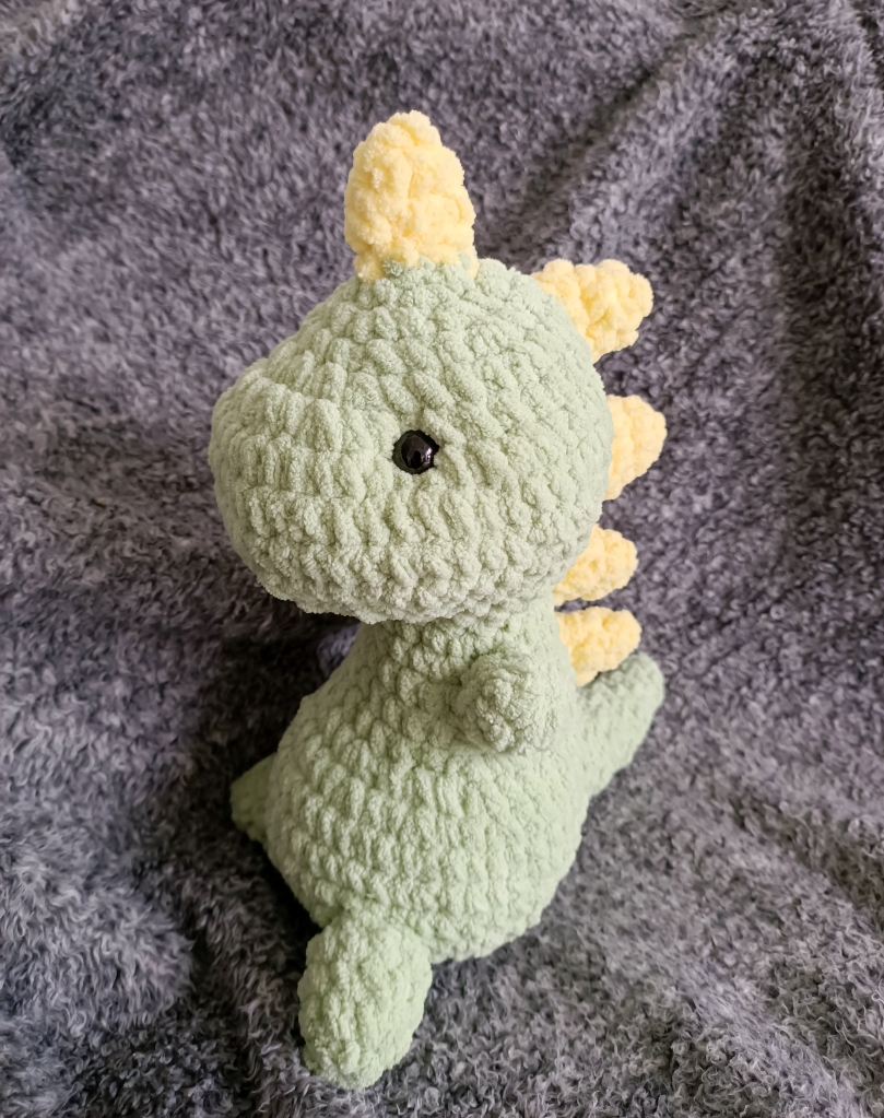 crocheted green dinosaur with yellow spikes on its head and back